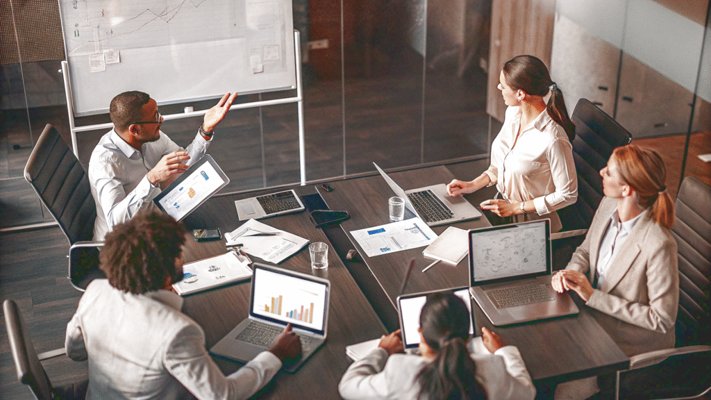 A group of SEO specialists gathered in a modern office, reviewing a project with laptops showing analytics and charts.